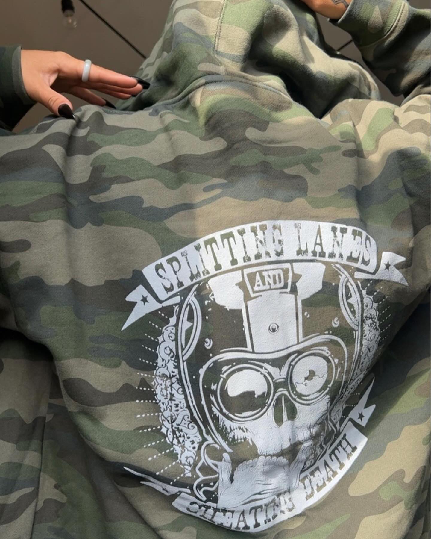 @rebecca.madrigal_ with the camo splitting lanes and cheating death zip up hoodie.  These things are awesome!  We are in stock and ready to ship!! Grab one now!  Link in the bio to see all our swag.